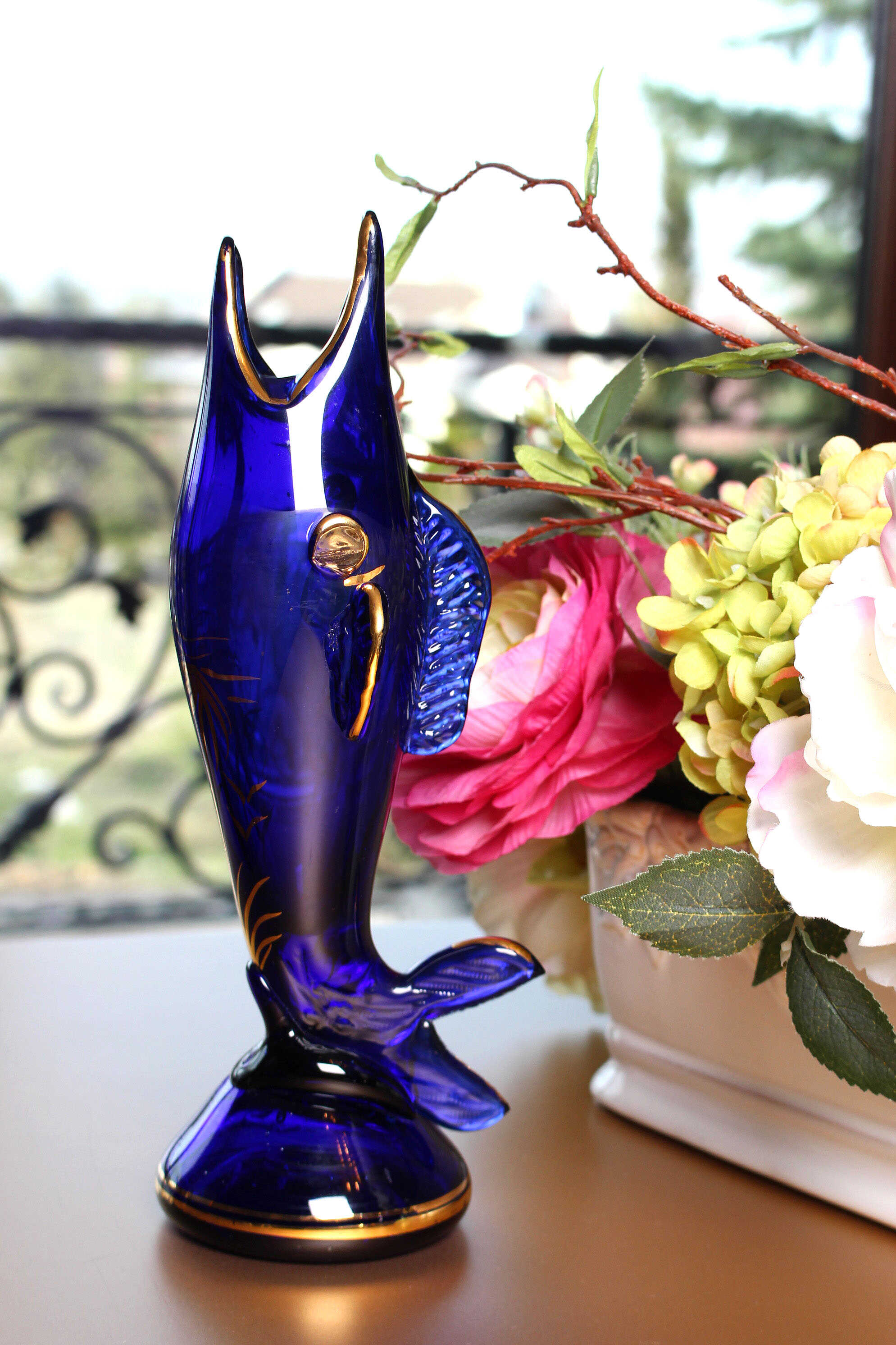 Seher Ayral El Sanatları için 1980’li yıllarda üretilmiş, el işçiliğiyle üfleme cam tekniğiyle şekillendirilmiş, altın yaldız süslemeli lacivert balık figürü dekoratif obje.